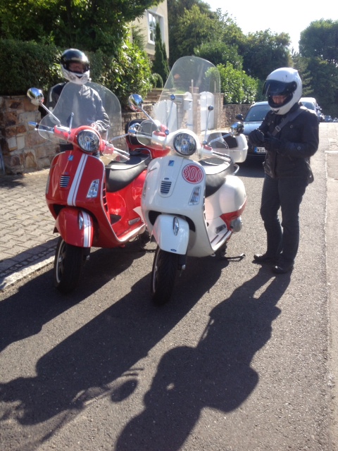 Zwei Menschen in Motorrad-Kluft neben ihren Vespas.
